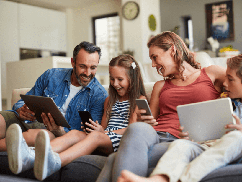 Father, mother and two children looking at devices.