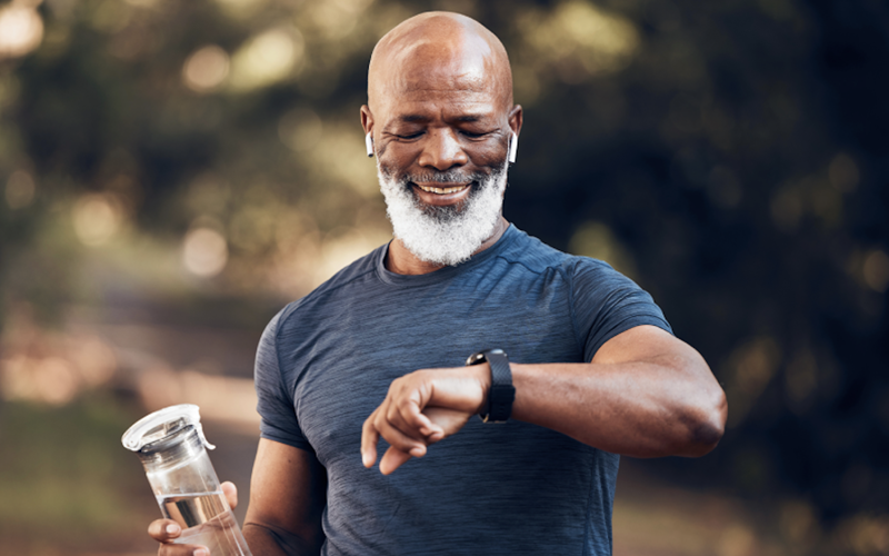 African American man exercising looking at his smart watch and holding a water bottle