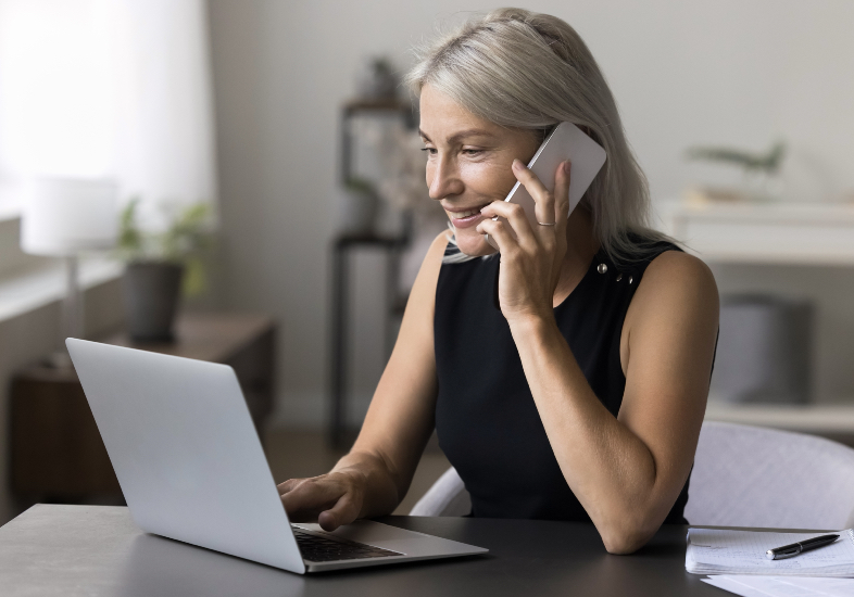 woman on phone in front of laptop